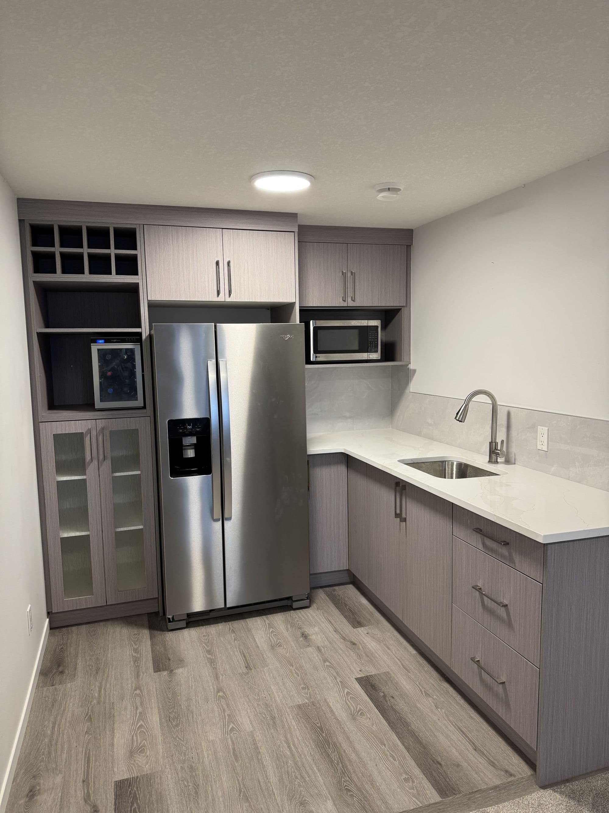 Modern kitchen renovation in Calgary featuring custom white cabinets, quartz countertops, and stainless steel appliances